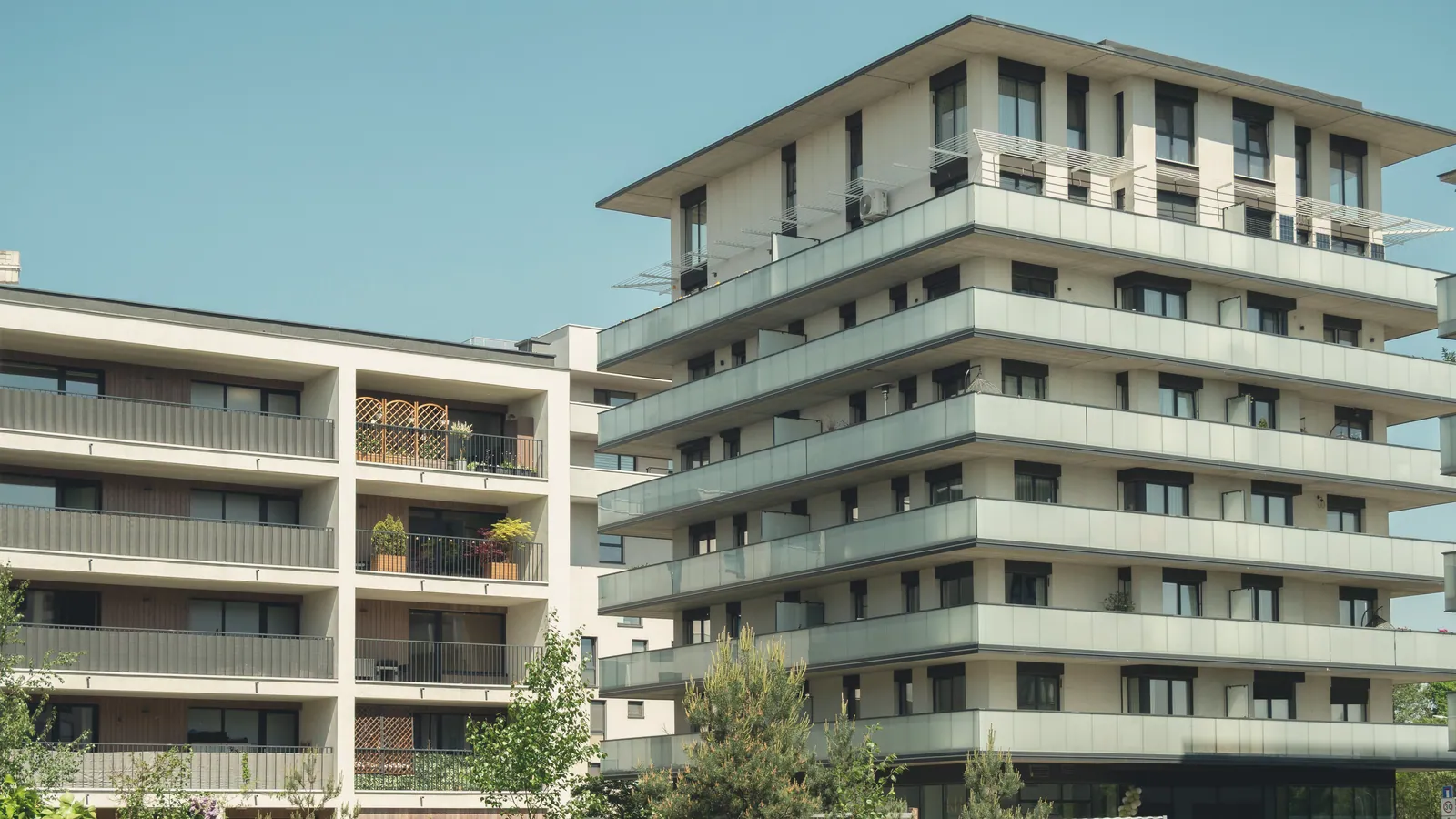 Clădiri de locuințe cu balcoane de sticlă și grădină, într-o după-amiază senină